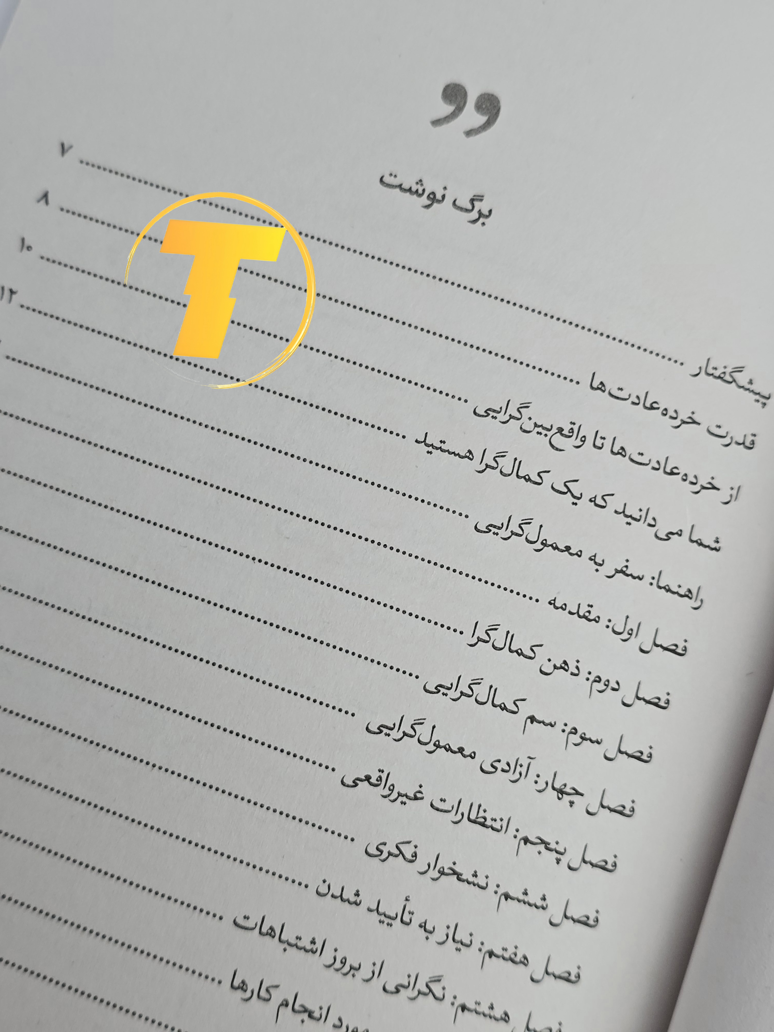 صفحات باز کتاب چگونه کمال‌گرا نباشیم – نمایی از چاپ تمیز، صفحه‌آرایی منظم روی میز سفید