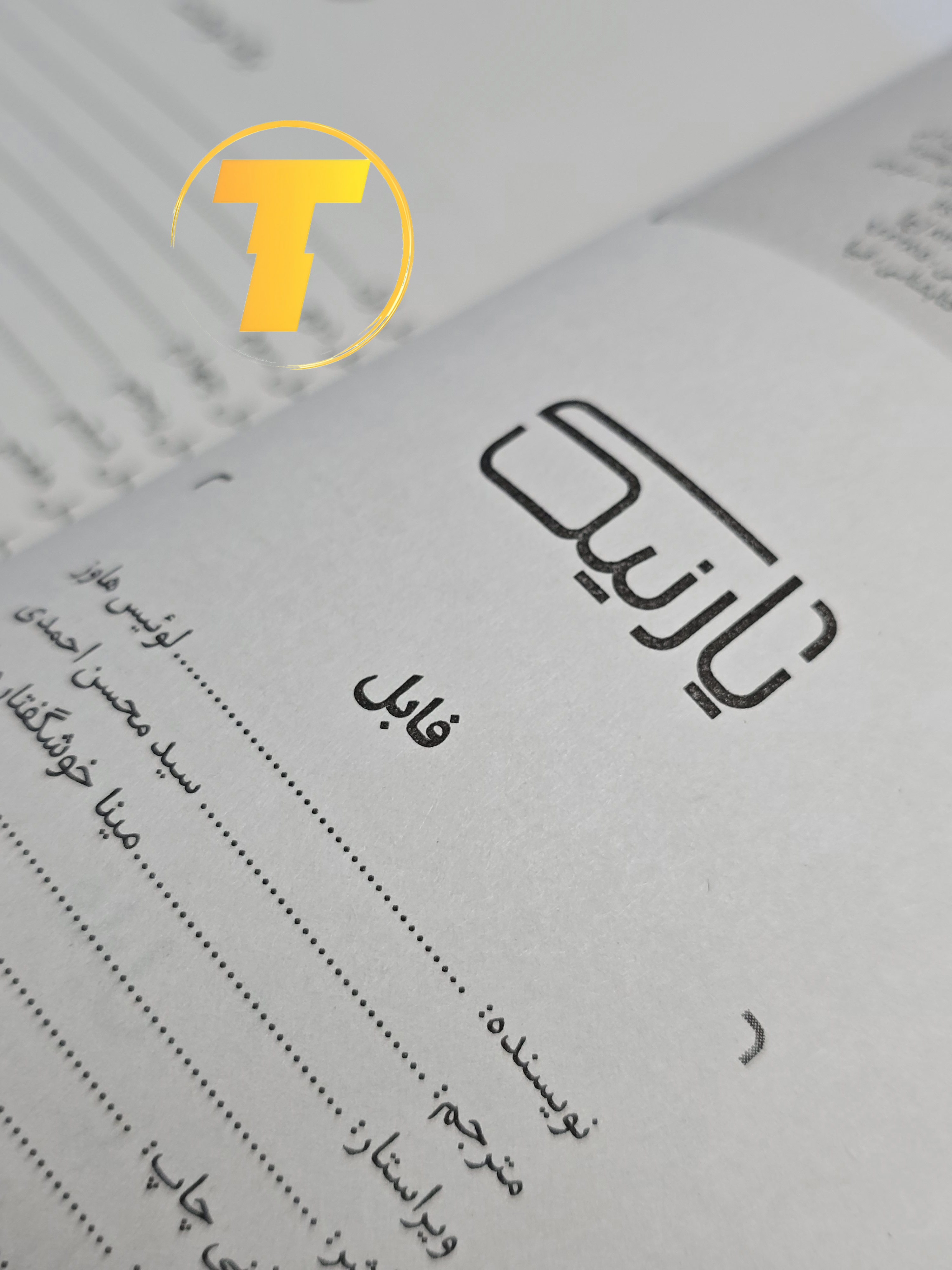 صفحات باز کتاب فابل – نمایی از چاپ تمیز، صفحه‌آرایی منظم و طراحی نشر یارنیک روی میز سفید