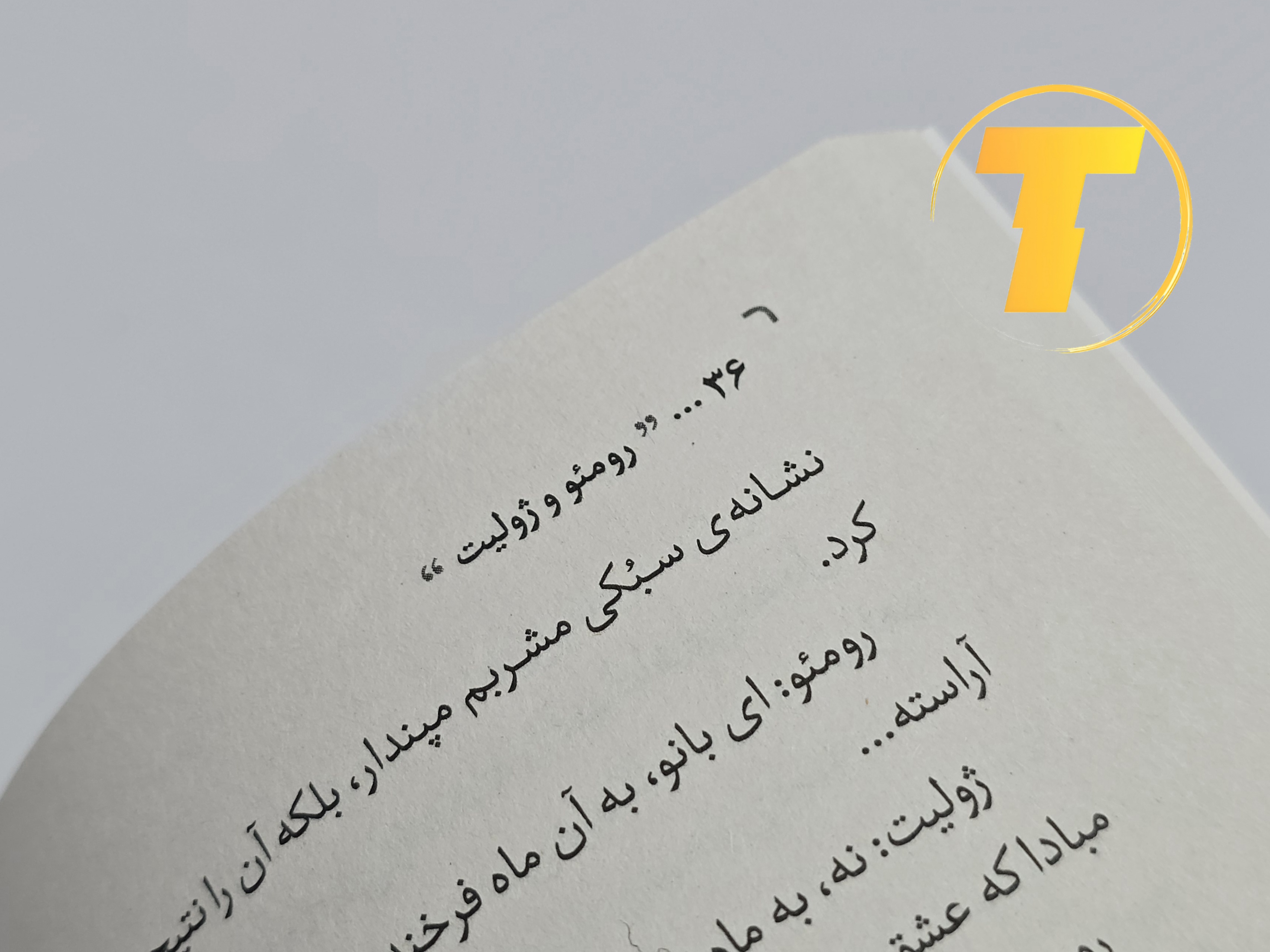 صفحات باز کتاب رومئو و ژولیت – نمایی از چاپ تمیز، صفحه‌آرایی کلاسیک و طراحی نشر آثار نور روی میز سفید