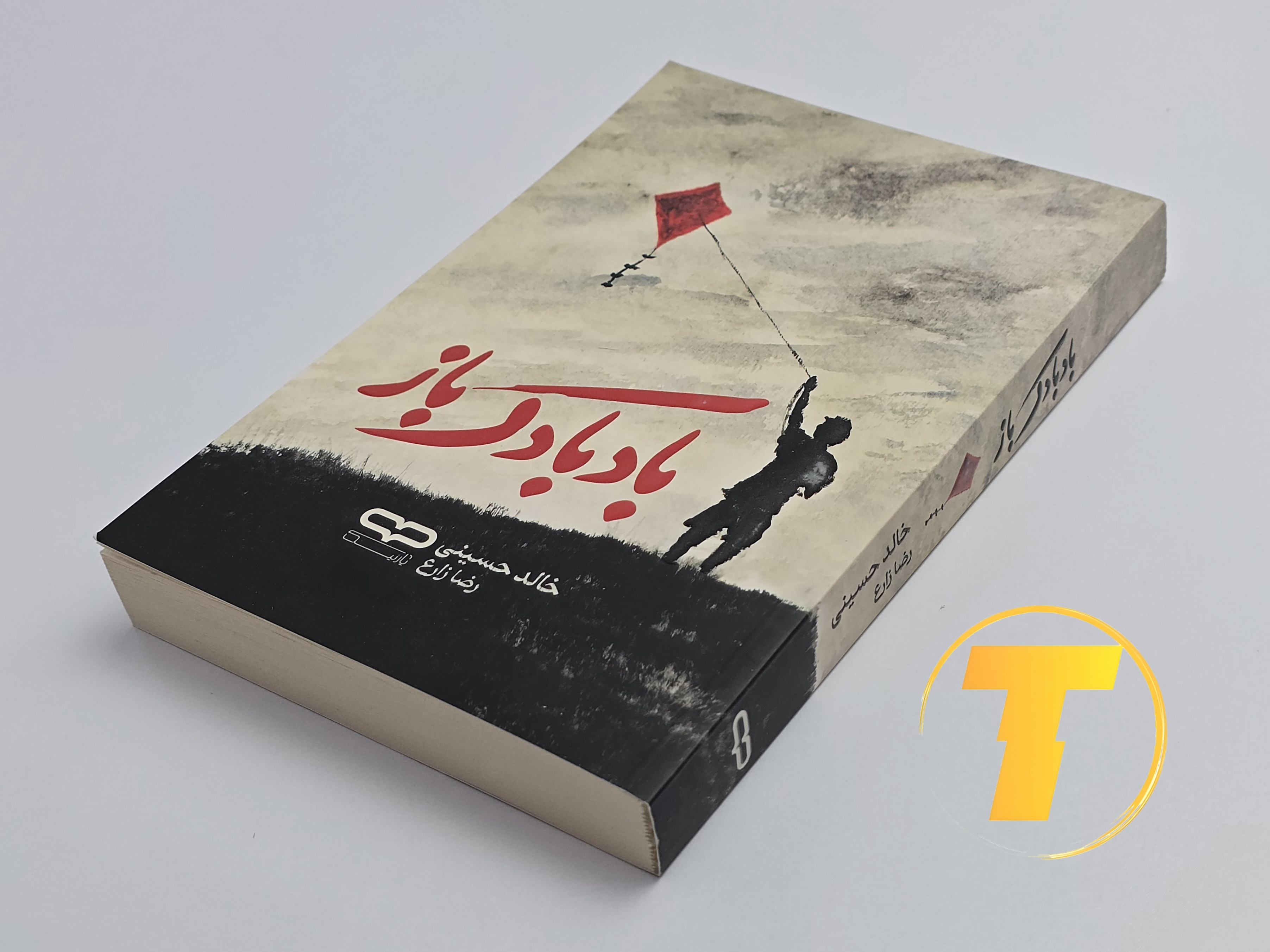 کتاب بادبادک‌باز روی میز سفید – تصویری از جلد و کناره‌های کتاب چاپ‌شده توسط نشر آثار نور