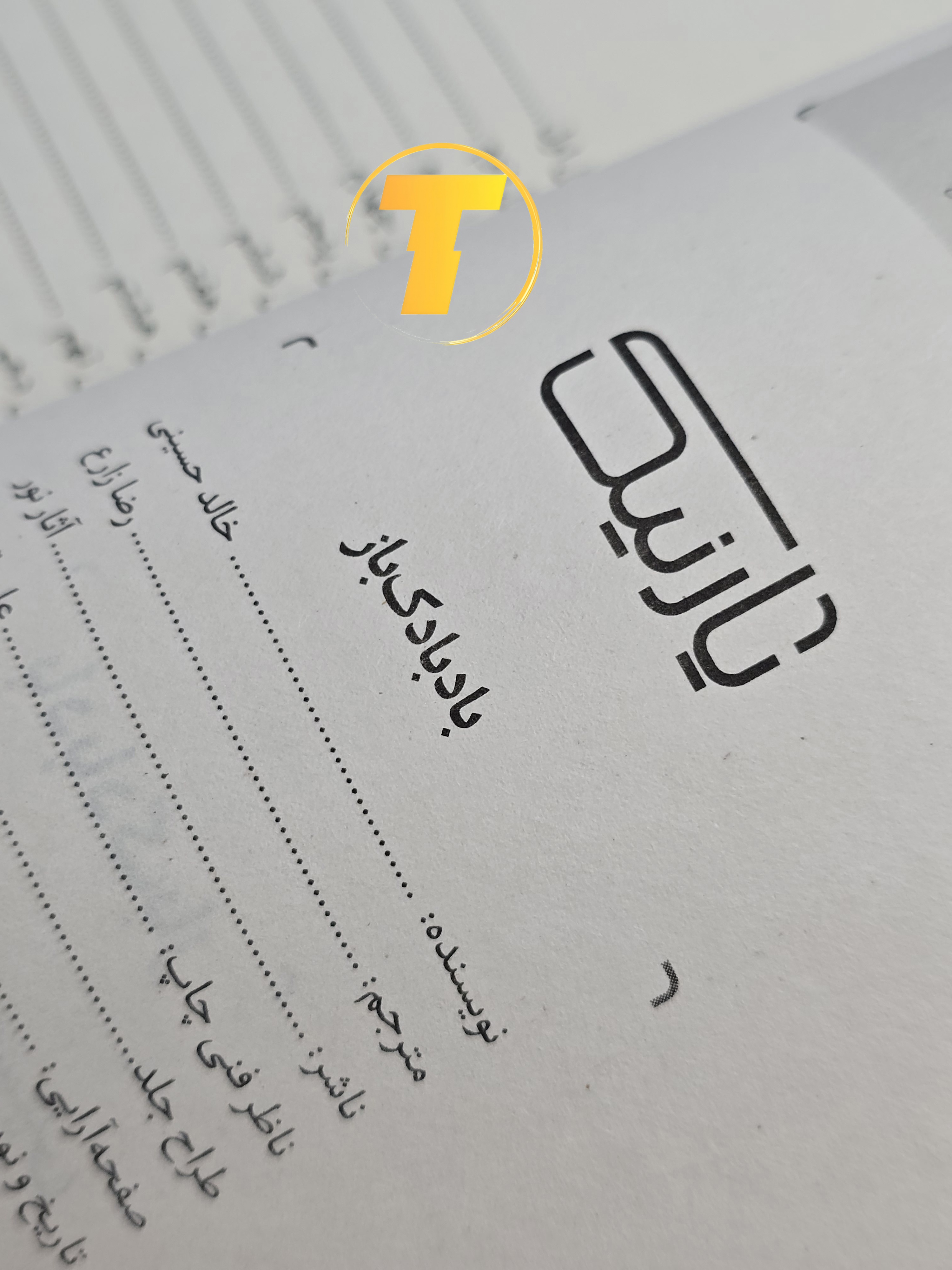 صفحات باز کتاب بادبادک‌باز – نمایی از چاپ تمیز، صفحه‌آرایی منظم و طراحی نشر آثار نور روی میز سفید