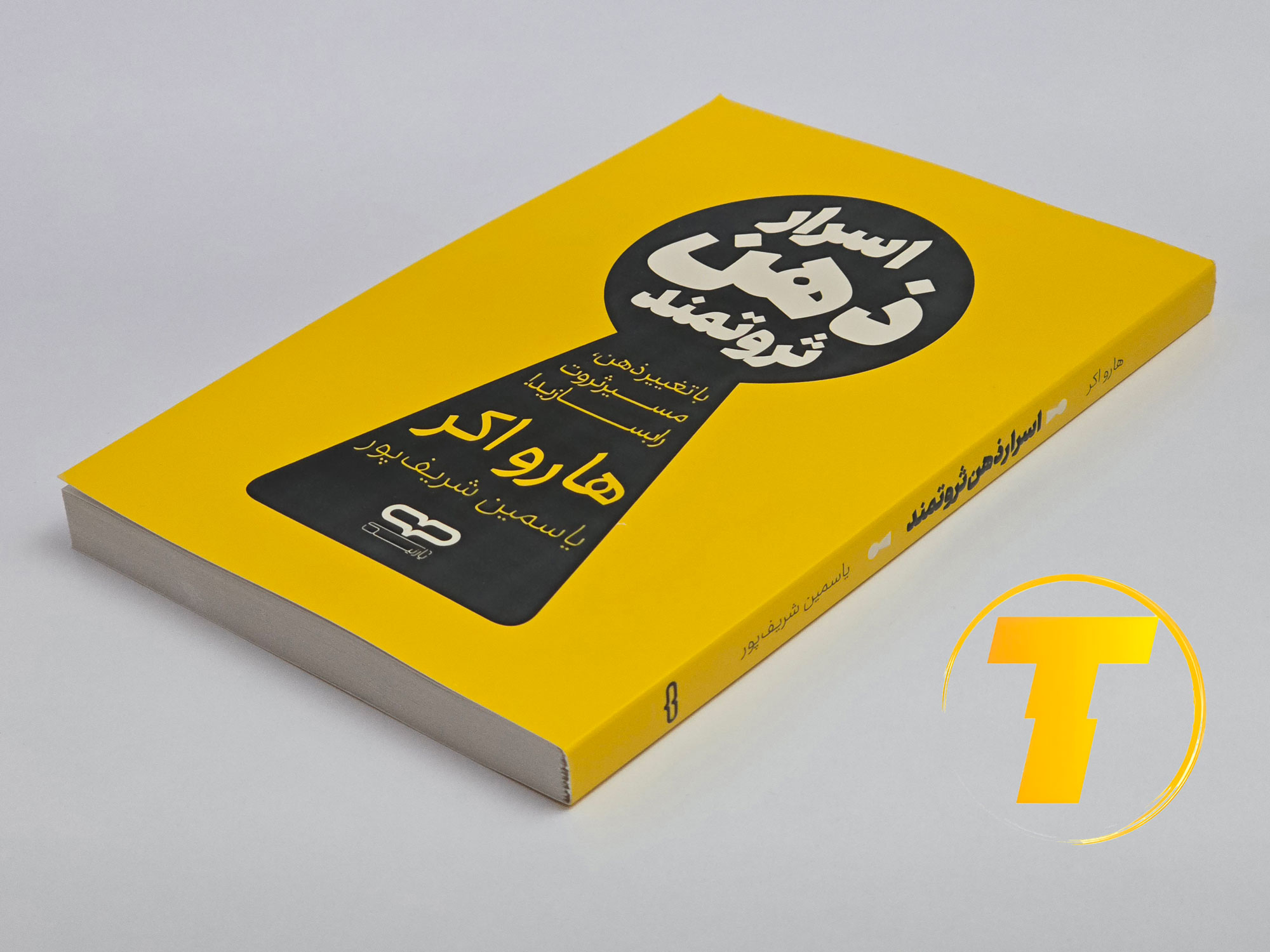 کتاب اسرار ذهن ثروتمند روی میز سفید – تصویری از جلد و لبه‌های کتاب چاپ‌شده توسط نشر یارنیک