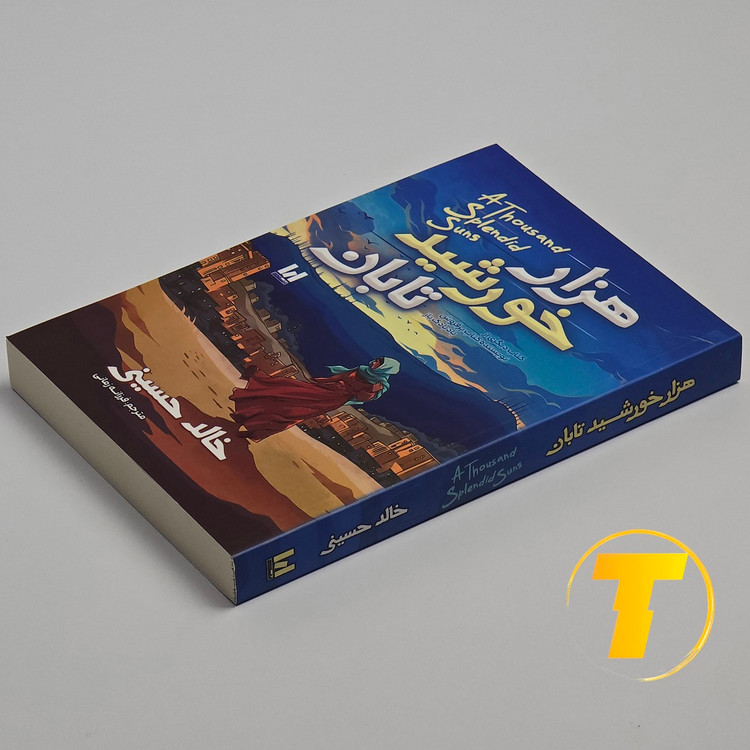 عکس کتاب شومیز هزار خورشید تابان روی میز مطالعه